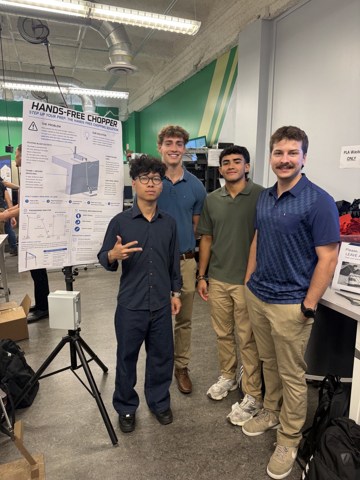Team standing with the Hands-Free Chopper poster at a design showcase
